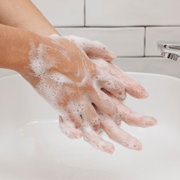 Washing hands rubbing with soap in the sink