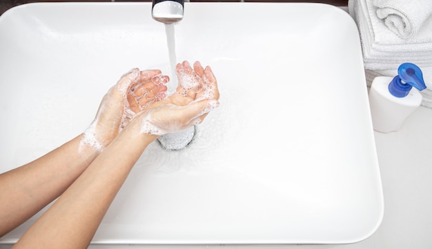 Lavarsi le mani con acqua saponosa sotto l'acqua corrente. il concetto di igiene personale e salute.