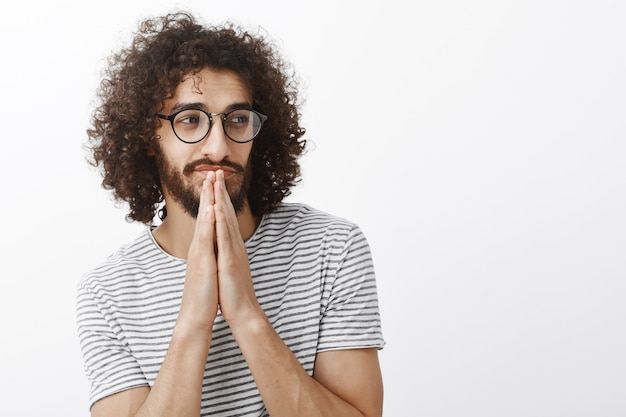 縞模様のtシャツを着て眼鏡をかけている、巻き髪のハンサムな軽薄なひげを生やした男性、よそ見とにやにや笑いのワシットアップショット