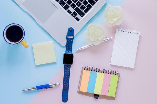 Watch and laptop near stationery and drink