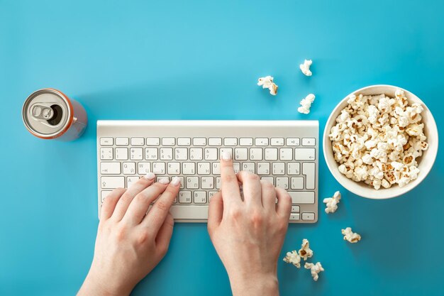 Watching movies with popcorn on a blue background flat lay