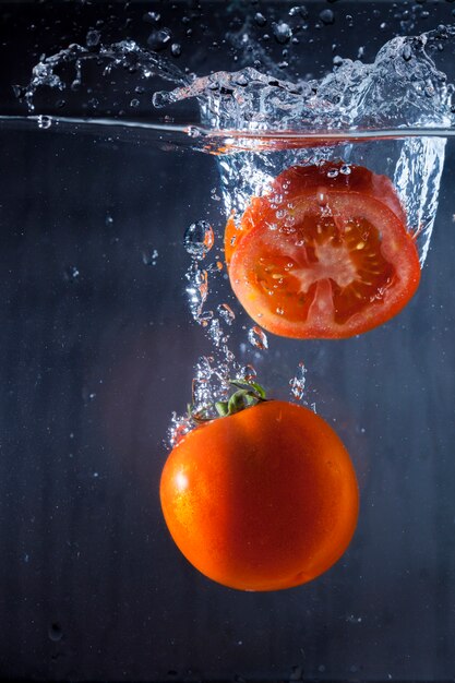 Water background with tomato and slice of tomato