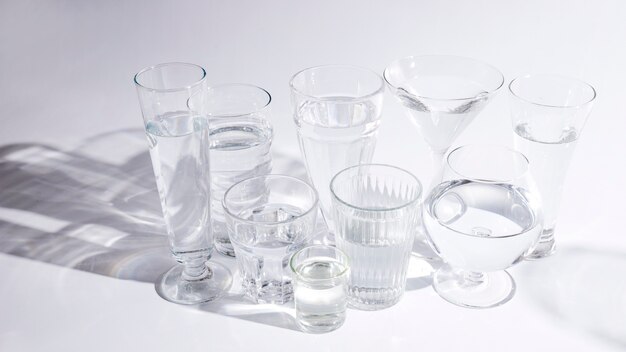Water in different type of glasses with shadow on white background