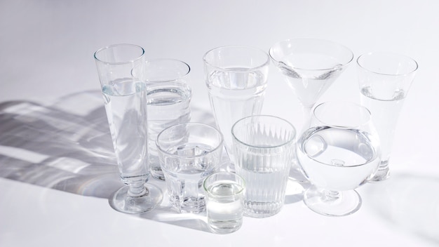 Вода в разных типах стаканов с тенью на белом фоне