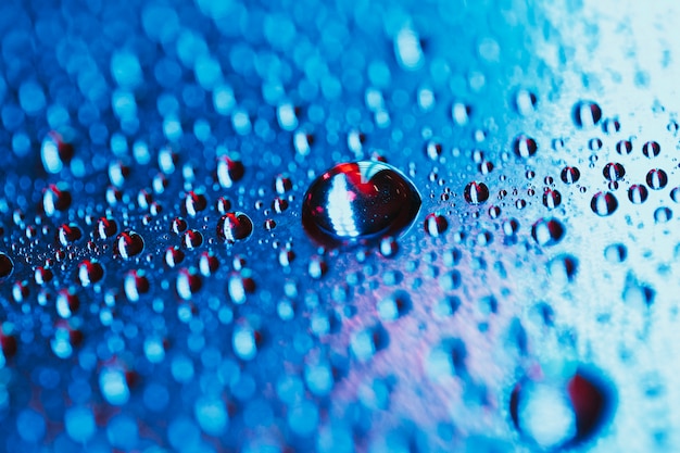 Water drop on the bright blue bokeh background