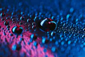 Free photo water droplets on glass bright blue and pink background