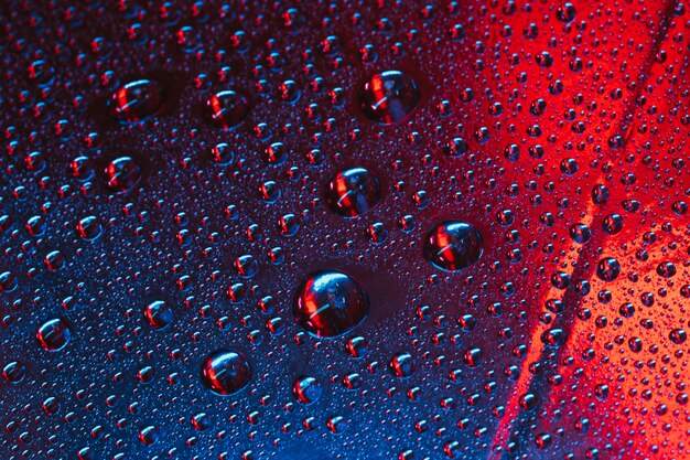 Water droplets on the glass with red and blue textured background