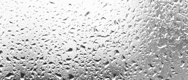 ガラス​の​後ろ​に​水​が​落ちる​。​窓​の​雨滴​から​の​背景​。​水​の​しずく​で​作られた​白黒​の​背景​。​クリエイティブ​な​パターン