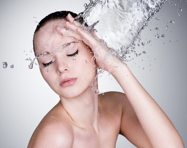 Water falling on the beautiful sensuality woman face with clean skin