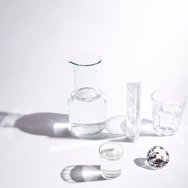 Water glasses; prism; sparkling diamond and beaker with shadow on white background