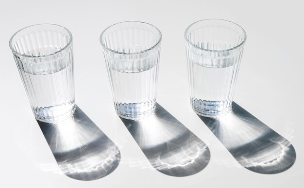 Water glasses with dark shiny shadow on white backdrop