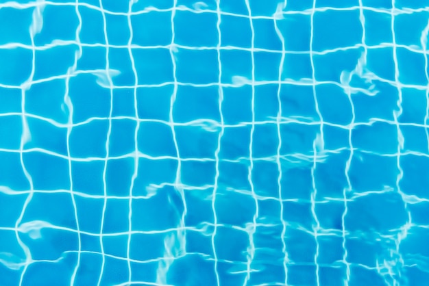 Ondulazioni di acqua su sfondo blu piscina piastrellata. vista dall'alto.