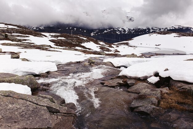 Water runs between the rocks covered with snow 