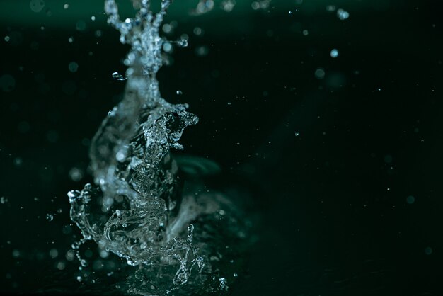 濃い緑色の背景に動きの水のしぶき