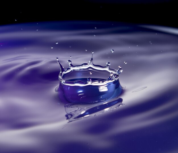 Всплеск воды в фиолетовых тонах с черным фоном