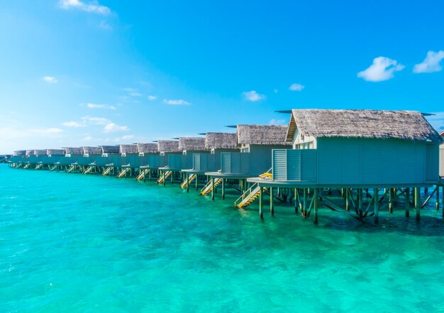 Водные виллы над спокойным морем на тропическом острове Мальдивы.