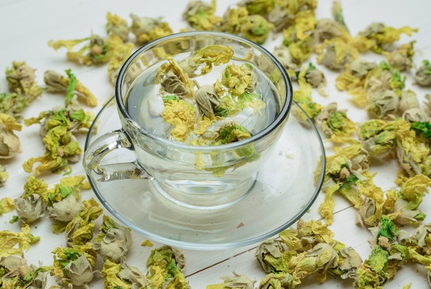 Free photo water with dried herbs in a cup on wooden table, high angle view.