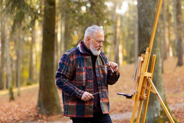 Free photo watercolor painting artist outdoors in the forest with easel and canvas