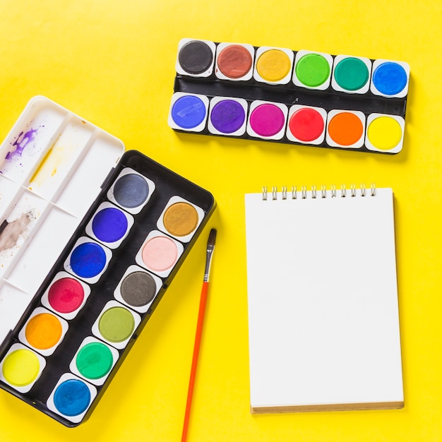 Free photo watercolor paints with notepad on table