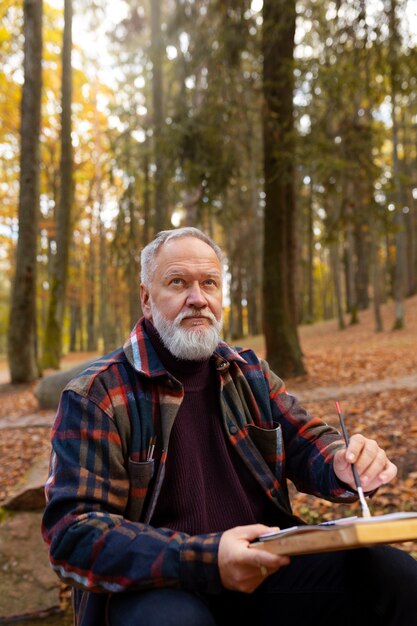 Free photo watercolorist painting outdoors in the forest