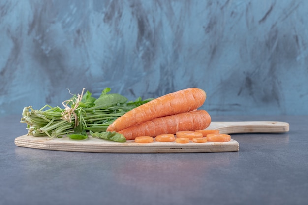 Watercress and carrots on the cutting board , on the marble surface.