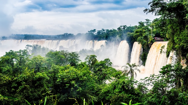 Waterfall at Iguazu National Park surrounded by forests covered in the fog under a cloudy sky