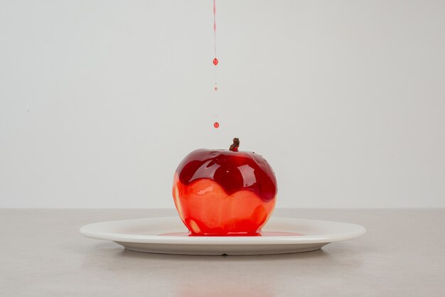 Watering an apple with syrup om white plate.