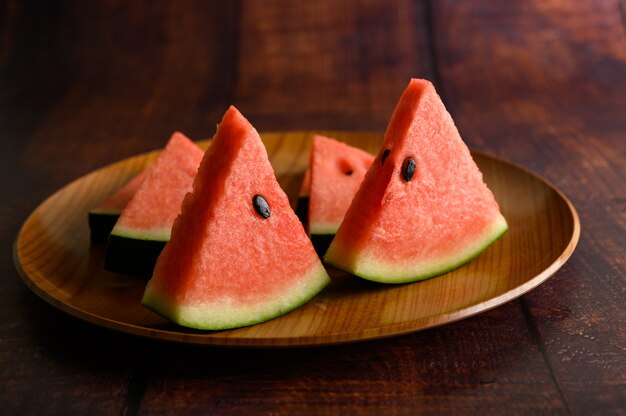 Watermelon cut into pieces in a dish on a wooden table.
