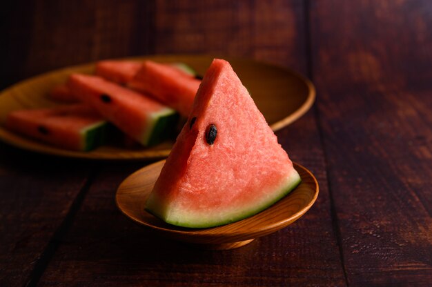 Watermelon cut into pieces in a dish on a wooden table.