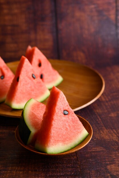 Watermelon cut into pieces in a dish on a wooden table.