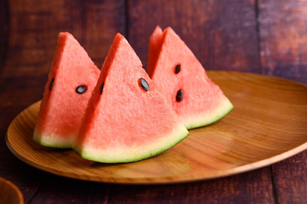 Free photo watermelon cut into pieces in a dish on a wooden table.