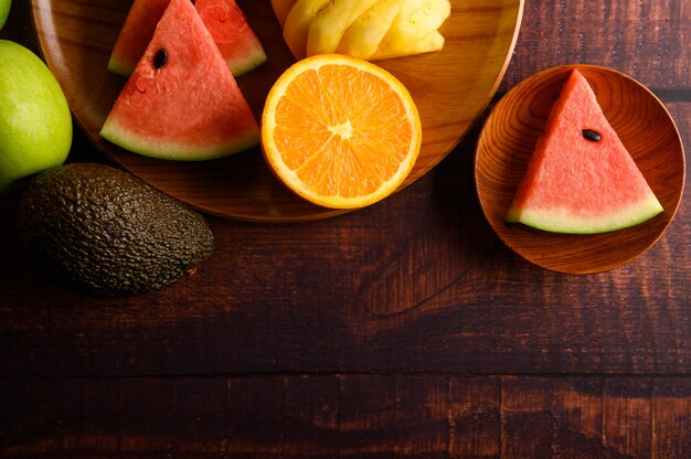 수박, 파인애플, 오렌지, 아보카도와 사과 나무 테이블에 조각으로 잘라. 평면도.