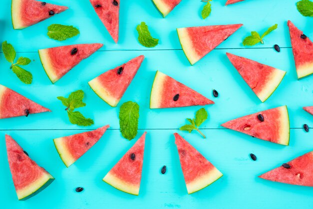 Watermelon slice with mint leaves on blue table