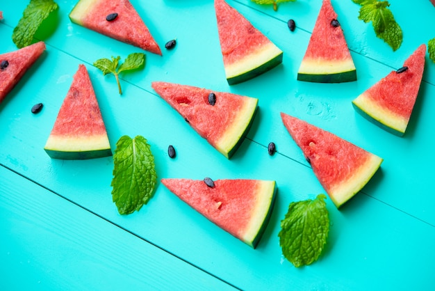 Free photo watermelon slice with mint leaves on blue table