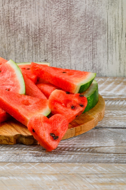 Watermelon slices on a cutting board on wooden and grunge background. side view.