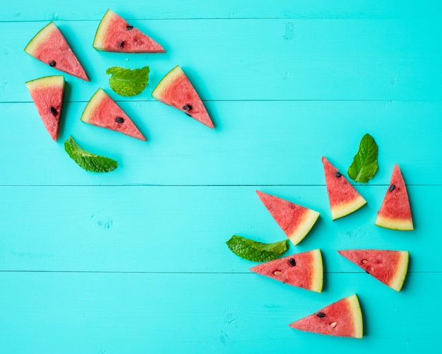 Watermelon slices with mint leaves on blue table