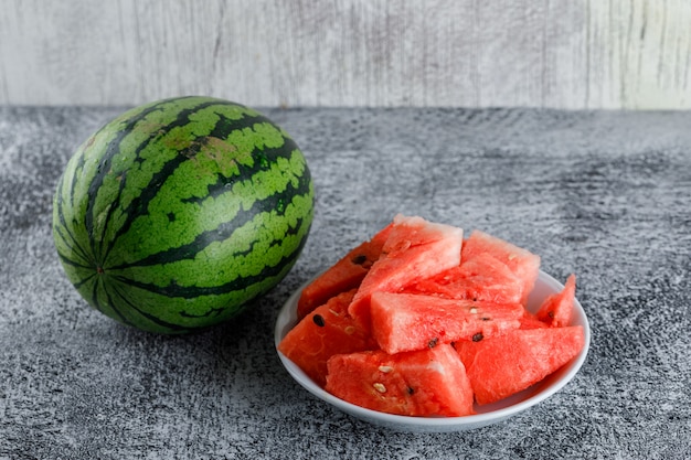 Free photo watermelon with slices on a grey grunge table