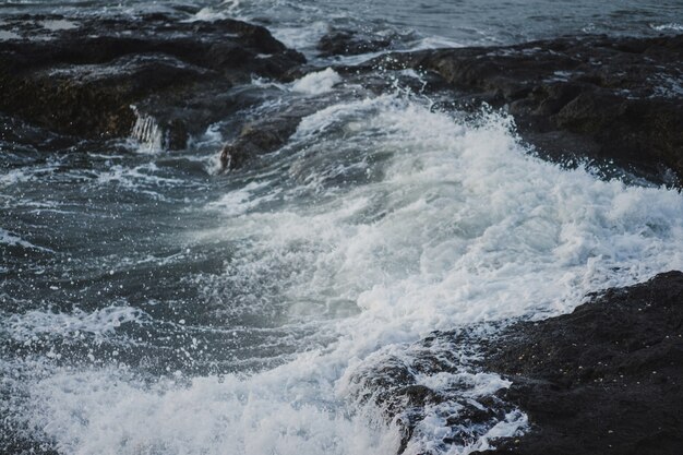 the waves of the ocean are breaking against the rocks. splashing ocean waves at sunset.