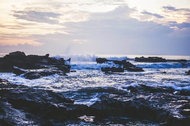 the waves of the ocean are breaking against the rocks. splashing ocean waves at sunset.