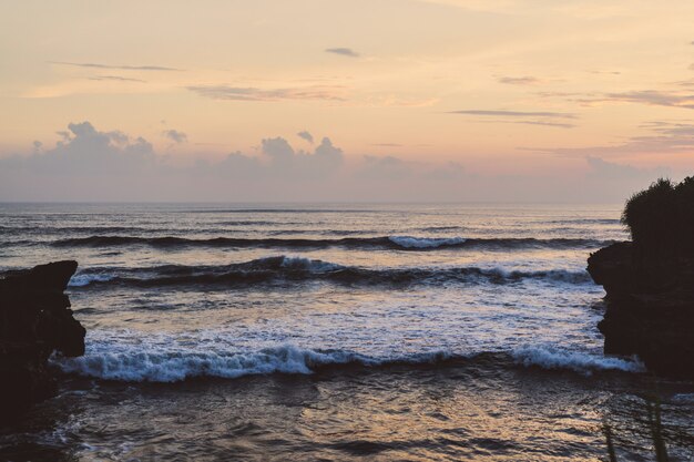 海の波が岩に砕けている。日没時に波が飛び散る。