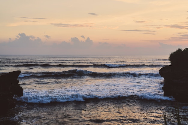 the waves of the ocean are breaking against the rocks. splashing ocean waves at sunset.