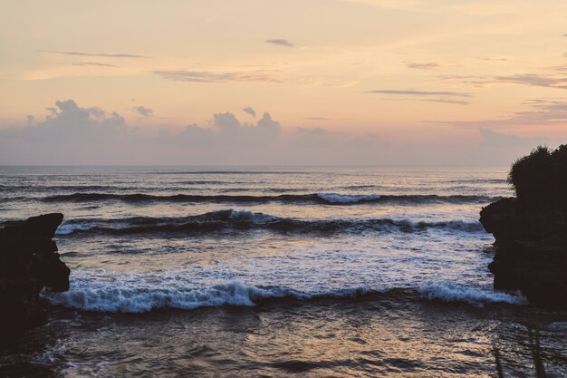 the waves of the ocean are breaking against the rocks. splashing ocean waves at sunset.