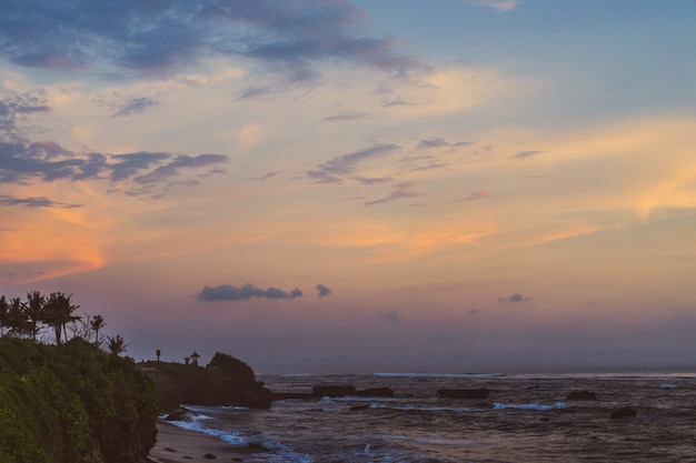 Foto gratuita le onde dell'oceano si infrangono contro le rocce. spruzzi onde dell'oceano al tramonto.