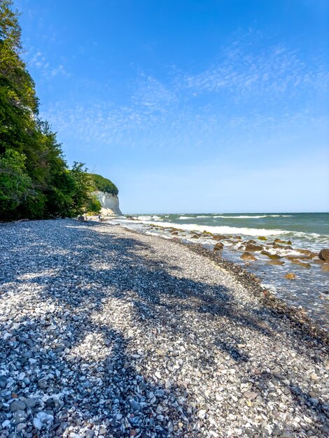 免费照片波在海岸线附近的海上空的卵石滩