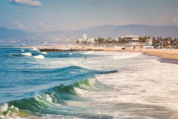 Wavy sea surrounded by hills and buildings under the sunlight in the evening