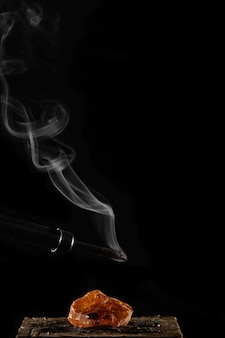 Wax candle with burning wick and smoke isolated on a black background