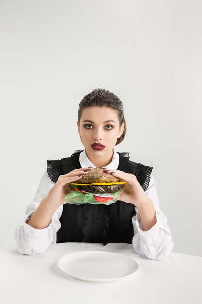 We are what we eat. Woman's eating burger made of plastic, eco concept. There is so much polymers then we're just made of it. Environmental disaster, fashion, beauty, food. Loosing organic world.