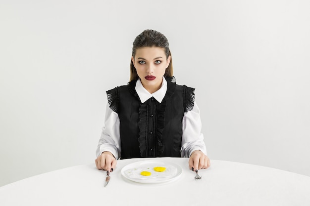 We are what we eat. woman's eating fried eggs made of plastic, eco concept. there is so much polymers then we're just made of it. environmental disaster, fashion, beauty, food. loosing organic world.