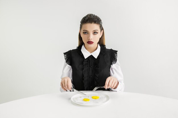 We are what we eat. Woman's eating fried eggs made of plastic, eco concept