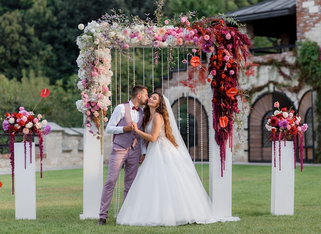 Wedding archway on the backyard and happy wedding couple outdoors before wedding ceremony